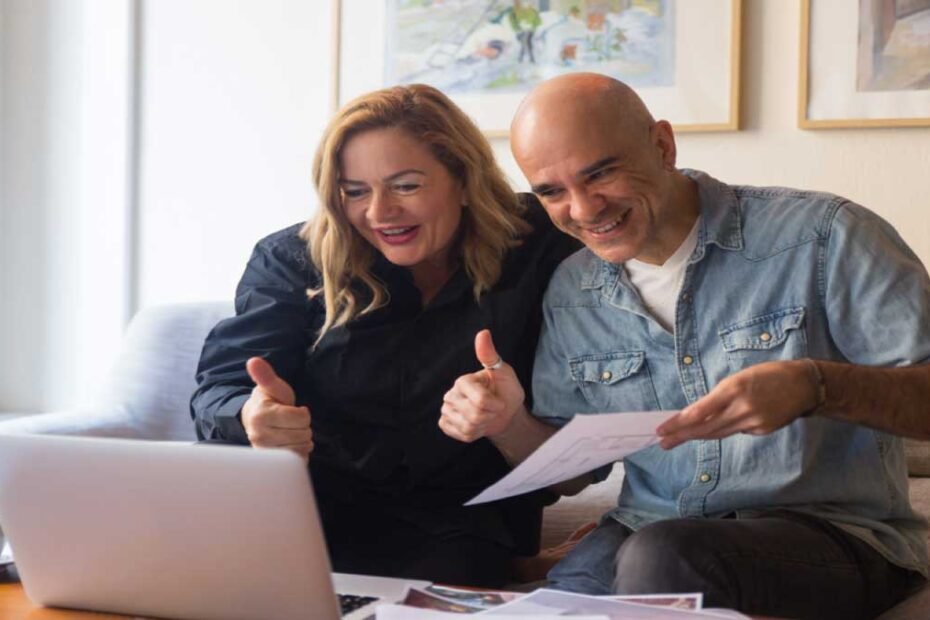 Casal na frente do computador felizes fazendo joia por contratar um seguro de vida resgatável.