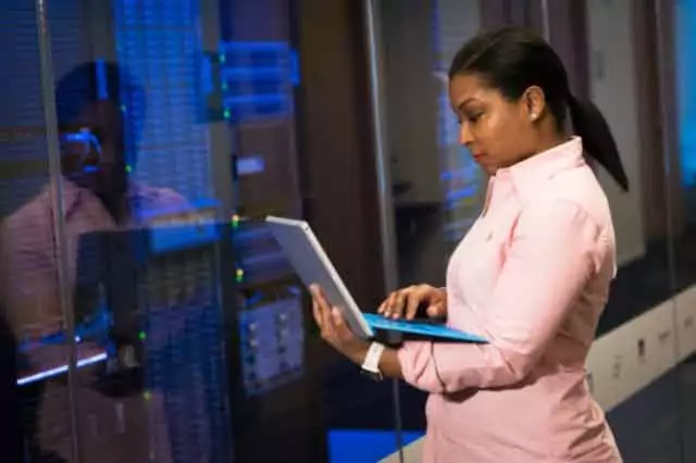 mulher segurando o computador em frente de um equipamento realizando avaliação patrimonial