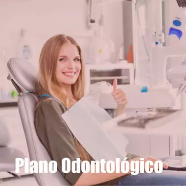 Mulher na cadeira de um dentista fazendo joia e feliz por possuir um plano odontológico